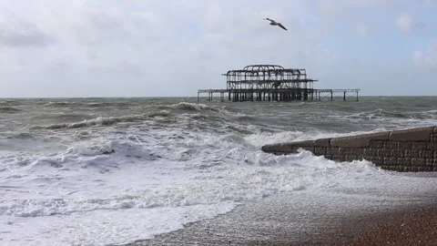 Slow-Mo of Windy Pebble Beach with High Waves, Burned Down Old Pier Video stock 287442651