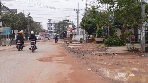 Slow mode motorbikes on a dirt road on Soksan Road in Cambodia Stock Footage