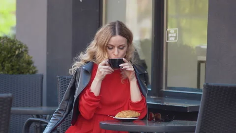 Slow morning drinking coffee. Romantic blonde in a red dress and biker jacket Stock Footage 155463547