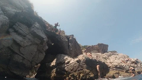 Slow motion 240 FPS man jumping from cliffs inside sea camera goes underwater Stock Footage 114325099