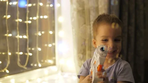 Slow motion. 3 years old caucasian boy playing with a water soap bubbles gun Stock Footage 232217564