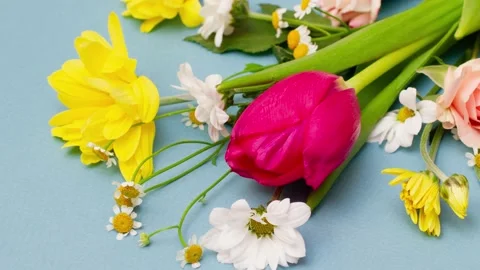 Slow motion 4k approaching a varied bouquet of spring flowers lying on a pastel Stock Footage 156078882