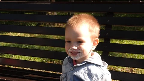 Slow motion 4k. The boy plays with ice cream sitting on a bench in the Park. The Stock Footage 94052366