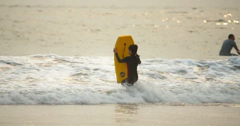 Slow motion 4K boy in surfing with yellow boogie board running into the ocean Video stock 140765924
