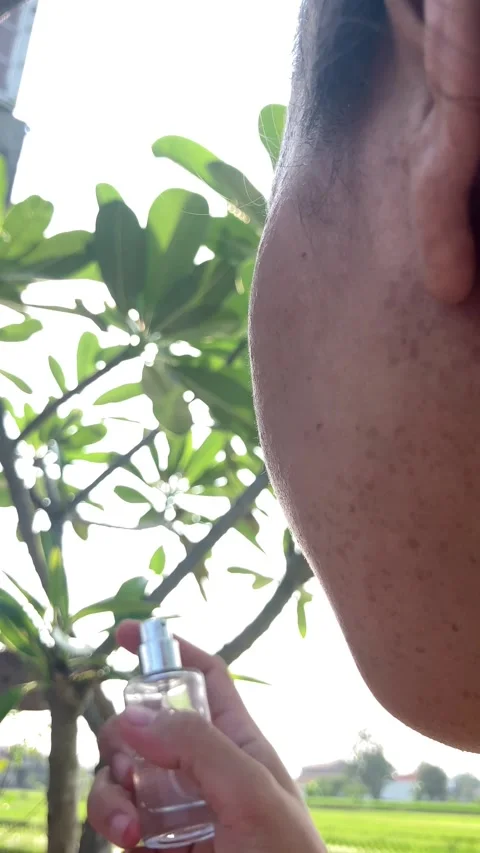 Slow Motion 4K Over the Shoulder of Young Woman Spraying Face Mist Summer Stockbeeldmateriaal 337641945