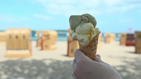 Slow motion 4K video of hand holding ice cream in cone waffle on a Baltic sea Stock Footage 155800756