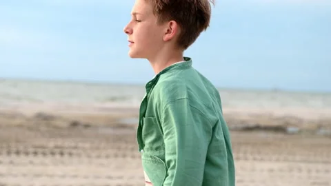Slow motion 4k video of portrait of handsome teen boy walking on sea beach Stock Footage 155885605