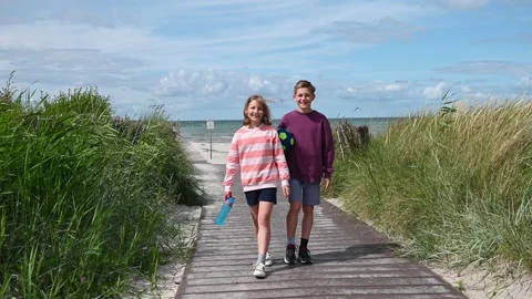 Slow motion 4K video of walking children on wooden pathway at white beach in Video stock 201823529