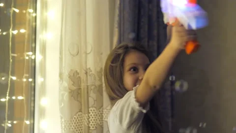 Slow motion. 5 years old caucasian girl playing with a water soap bubbles gun Stock Footage 232217729