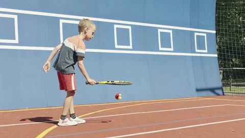 Slow motion. 7-Year-Old Boy Practicing Tennis by Bouncing a Ball on His Racket Stock Footage 342174815