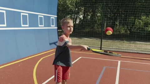 Slow motion. 7-Year-Old Boy Practicing Tennis by Bouncing a Ball on His Racket 스톡 동영상 342174826