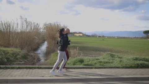 Slow motion: Active couple run during a sunny day in their leisure Stock Footage 150503179