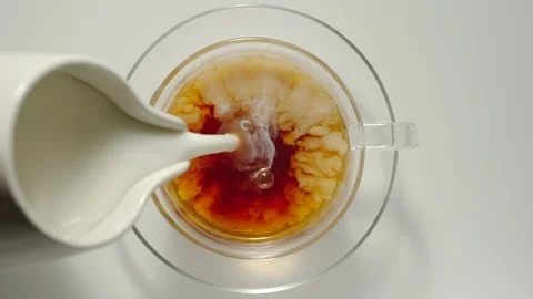 SLOW MOTION: Adding Milk From Milk Jug Into A Cup Of Black Tea Stock Footage 117648941