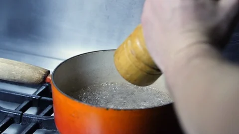 Slow motion - Adding pepper to boiling pan of water on kitchen hob Stock Footage 86534492