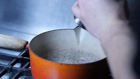 Slow motion - Adding pepper to boiling pan of water on kitchen hob, chef cook Stock Footage 86534820