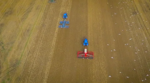 Slow motion aerial drone view of tractors ploughing and birds flying Stock Footage 59864618