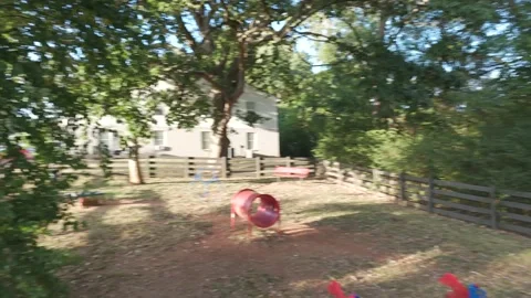 Slow motion aerial pan along fence line toward sunlit road at golden hour Stock Footage 346669013