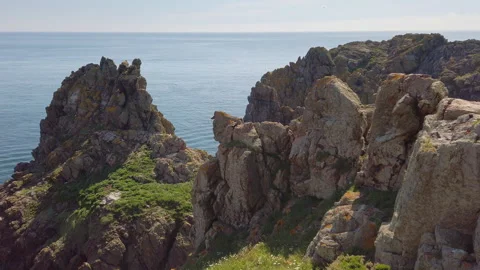 Slow motion aerial panorama of cliffs, sea-stacks. The 'Pea Stacks', Guernsey Stock Footage 252925972