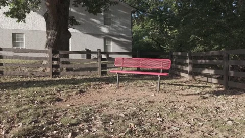 Slow motion aerial past red park bench and wooden fence at sunset Stock Footage 346732406