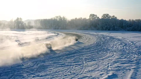 Slow motion aerial shot of two cars drifting on the ice of a frozen lake. Stock Footage 169452178