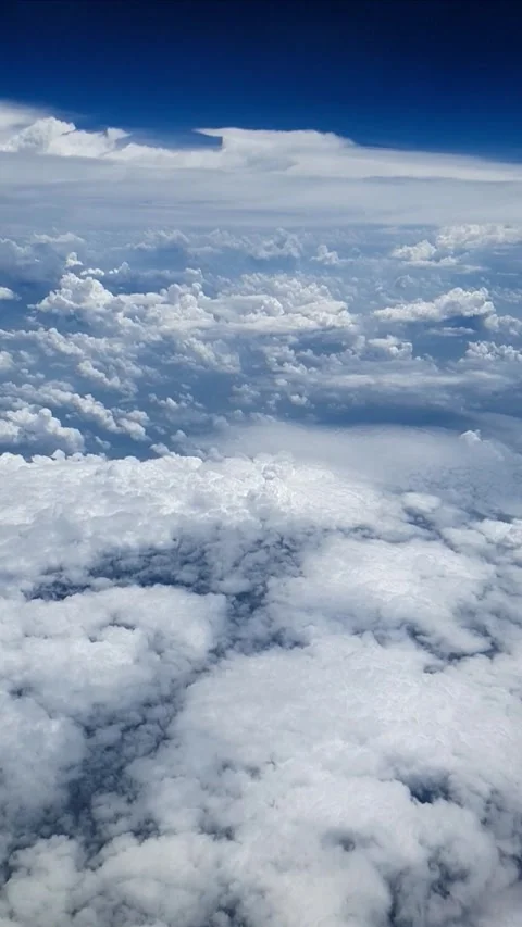 Slow motion aerial view above soft white clouds under deep blue sky. Vertical ci Stock Footage 331888169