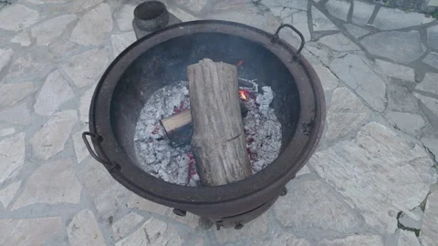 A slow-motion aerial view of a fire pit with two logs slowly catching fire Stock Footage 289560614