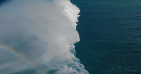 Slow motion aerial view of giant blue ocean wave crashing Stock Footage 231200760