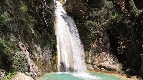 Slow-Motion Aerial View of Neda Waterfall and Emerald Pool on a Sunny Day Stock-Footage 303995420