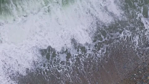 Slow motion aerial view of small waves crashing onto the beach Stock Footage 313526391