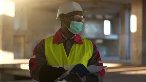 Slow Motion African american builder in medical mask looks in work papers Stock Footage 199290836