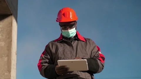 Slow Motion African american builder in medical mask makes notes in tablet PC Stock Footage 210547939