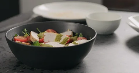 Slow motion almond flakes falling on salad with chicken, arugula and tomatoes in Stock Footage 128646707