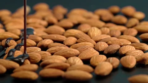 Slow motion almonds are poured with chocolate on a black background Vídeo Stock 148221922