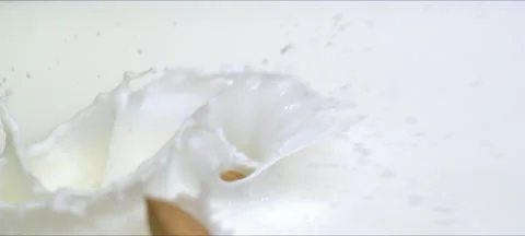 Slow motion almonds falling into milk. Milky splash. Commercial shot Stock Footage 323439362