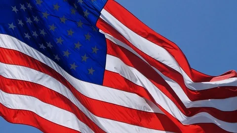 Slow Motion American US Flag Waving in Wind Against a Blue Sky Stock Footage 94880111