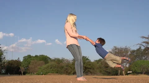 Slow motion and low angle view of mother playing and swinging child around in a Stock Footage 46376526