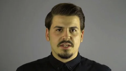 Slow motion angry young man screaming to camera. Grey dark background. Stock Footage 76203450