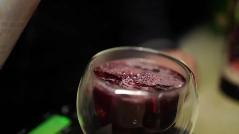 Slow motion Aperol-style liquid mixing into berry tea in cocktail glass Stock Footage 311667554