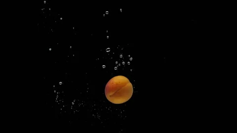 Slow motion apricot spinning falling into transparent water on black background Stock Footage 164088752