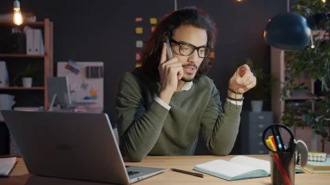 Slow motion of Arab man making mobile phone call discussing work in office at Stock Footage 135299200