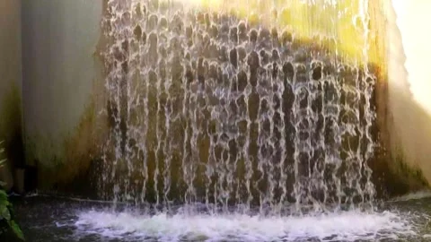Slow motion of an artificial waterfall, water falling slowly in a public park.  Video stock 276573491