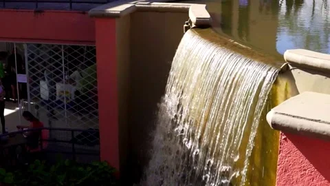 Slow motion of an artificial waterfall, water falling slowly in a public park. Stock Footage 276573862