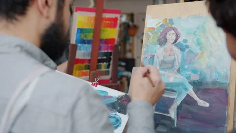 Slow motion of artist master teaching female apprentice painting portrait in Stock Footage 137999314