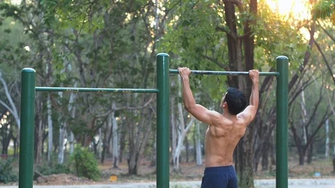 Slow motion Asia Muscular man doing pull-ups on horizontal bar at playground. Stock Footage
