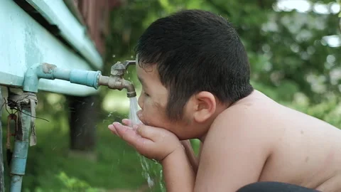 Slow motion of Asian boy drinking outdoors fresh water from tap Stock Footage 154525432