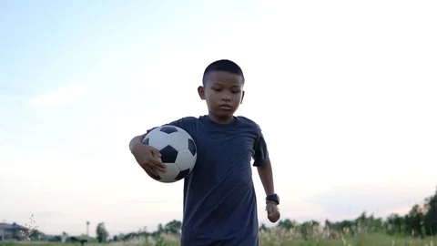 Slow motion, Asian boy holding a soccer ball and ran happily on the prairie. Stock Footage 111576894
