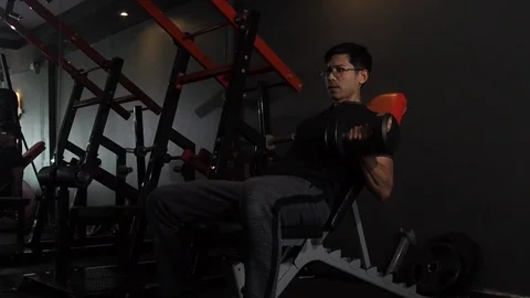 Slow motion Asian man lifting weights seated dumbbell  curl in gym. Stock Footage 106290705