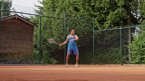 Slow motion. An athlete engages in a focused tennis practice on a vibrant clay Video stock 313601512