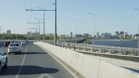 Slow Motion Automobiles Drive near Dam against Cityscape Stock Footage