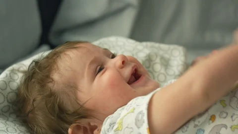 Slow motion of baby lying in bed trying to grab toes Stock Footage 114645071